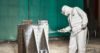 Worker wearing Lakeland MicroMax NS Coverall while spray painting products in a warehouse