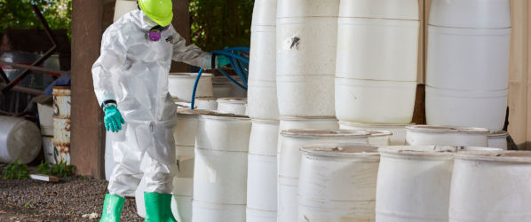 Worker wearing Lakeland ChemMax 2 while filling barrels.