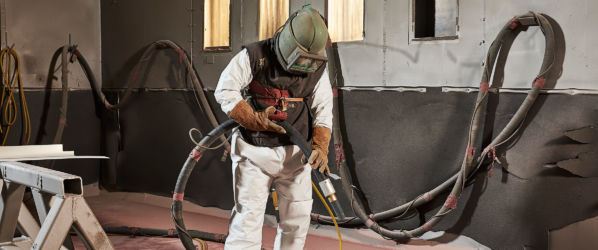 Worker wearing Lakeland MicroMax NS Coverall to sand blast parts in an industrial facility.