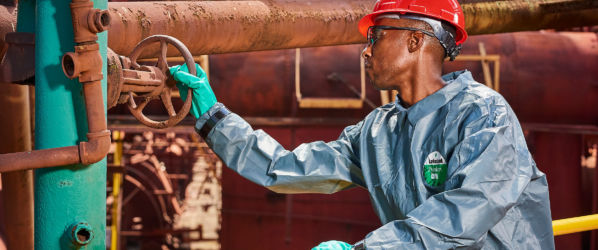 Worker wearing Pyrolon CRFR Coverall while turning wheel valve in an industrial plant.