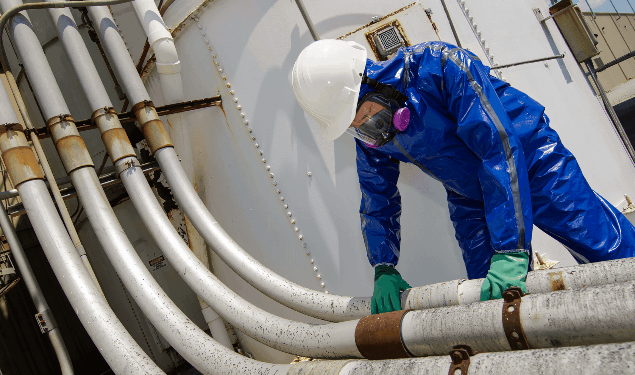 Worker wearing a Lakeland Pyrolon CBFR Coverall and a respirator while working in an industrial facility.